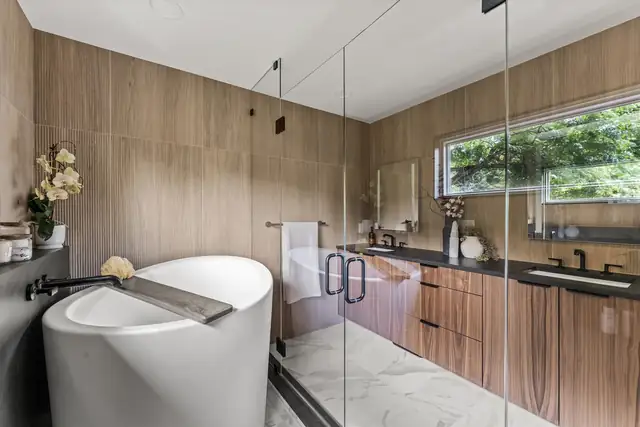 Huron River primary suite bathroom with a freestanding tub, wood-look wall tile, a glass shower and a floating wood vanity