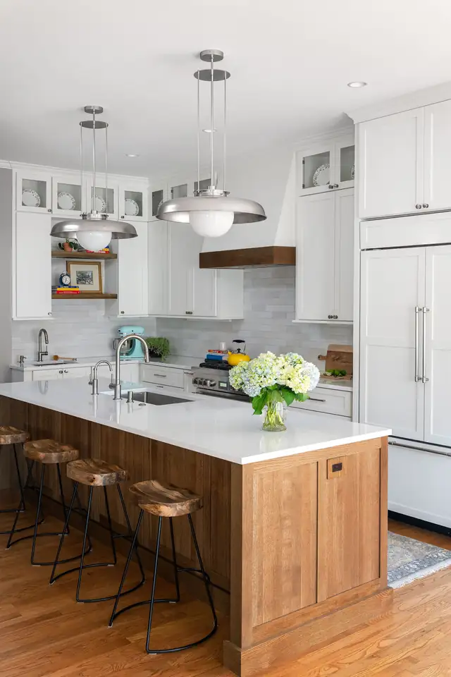 White kitchen by Ann Arbor Remodeling with a stained wood island, white quartz top, three metal pendants and leather counter stools