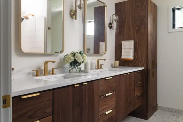 Bathroom in the Emerald Addition with a walnut double vanity, brass faucets and brass-framed mirrors