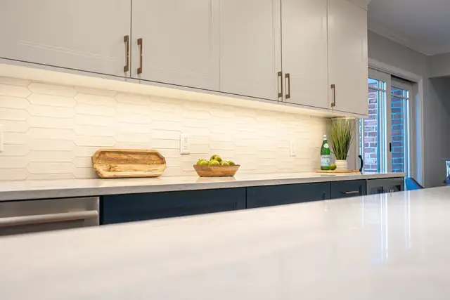 Kitchen with white upper cabinets, navy lower cabinets, a white quartz counter and a cream picket tile backsplash