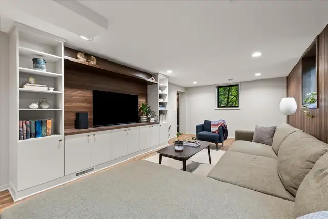 Living room with white built-in shelves, a wood media wall and a large sectional sofa