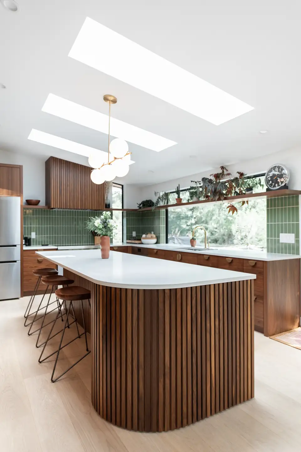 Design-build remodeling in Ann Arbor: mid-century kitchen with a fluted wood island, green tile backsplash, skylights and a globe pendant by Ann Arbor Remodeling