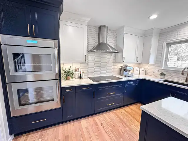 Kitchen remodel with navy lower cabinets, white upper cabinets, double stainless wall ovens and white zigzag wall tile